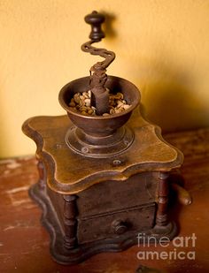 an old fashioned metal grinder sitting on top of a wooden table next to a wall