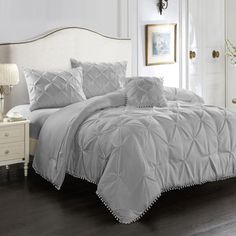 a white bed sitting in a bedroom next to a dresser and lamp on top of a hard wood floor