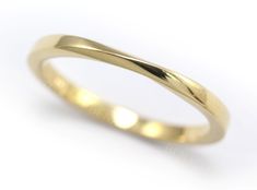 a yellow gold wedding ring with curved edges on a white background, close up view