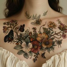 a woman's chest with flowers and butterflies painted on the back of her shoulder