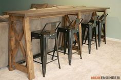 four stools and a table in the corner of a room with a couch behind it