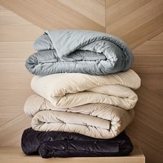 a stack of pillows and blankets sitting on top of each other next to a wooden wall