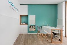 an office with white and blue walls, wood flooring and desks in the center