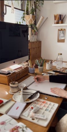 a person sitting at a desk with a computer monitor and paper in front of them