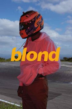 a man wearing a helmet and standing next to a road with the word blond on it