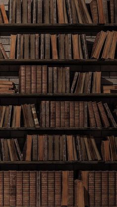 an old bookshelf filled with lots of books on top of wooden shelves next to a brick wall