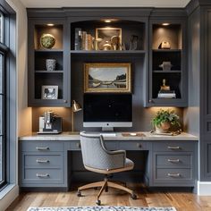 a home office with built - in desk and gray cabinets