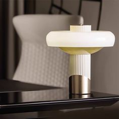 a lamp that is sitting on top of a table in front of a white chair