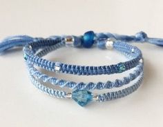 three bracelets with blue beads and glass bead on white table top next to each other