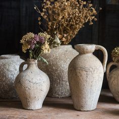 three vases with flowers in them sitting on a table next to other vases