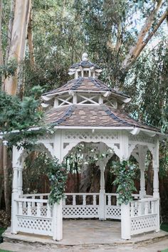 a white gazebo surrounded by trees and greenery