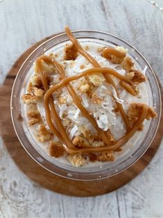 a dessert in a glass bowl on top of a wooden board with caramel toppings