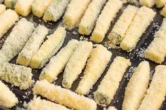 several pieces of fried food are on a baking sheet with grated parmesan cheese