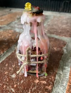 a bottle with some liquid on top of it sitting on the ground in front of a brick wall