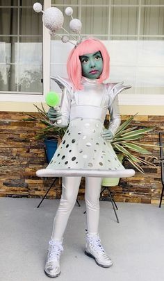 a woman dressed in white with pink hair and green eyes is holding a tennis ball