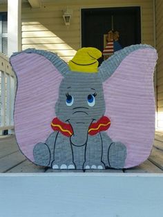 an elephant with a hat on top of it's head sitting in front of a house