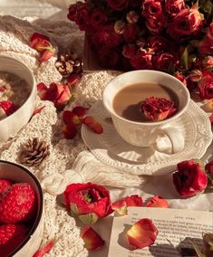 two cups of coffee on a table with roses and an open book next to it