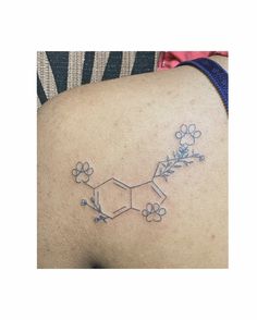 a tattoo on the back of a woman's shoulder with flowers and chemical symbols