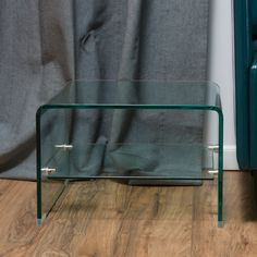 a glass table sitting on top of a hard wood floor next to a blue couch