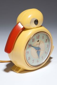 a yellow alarm clock sitting on top of a white table next to a red cord