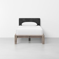 a bed with white sheets and black headboard in a minimalistic style bedroom setting