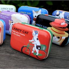 there are many small tins that have cats on them and one has a cat riding a bike