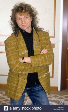 a man with curly hair wearing a jacket and jeans