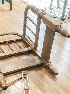 a wooden bed frame laying on top of a hard wood floor next to a pair of scissors