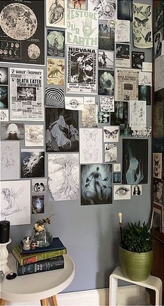 a wall covered in pictures and posters next to a table with a potted plant