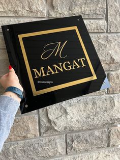 a person holding up a sign in front of a brick wall that says mangoat