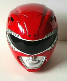 a red motorcycle helmet with shark teeth on it's face and the mouth is painted black