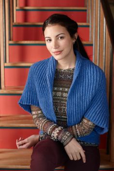 a woman sitting on the steps wearing a blue cardigan