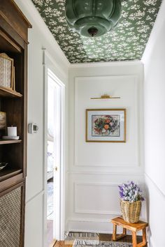 a room with white walls and floral wallpaper on the ceiling, along with a wooden bench