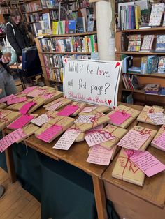 many pieces of paper are on the table in front of bookshelves with pink notes attached to them