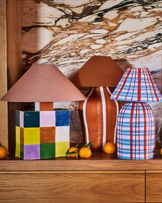 three vases and two lamps on a shelf