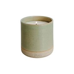 a small ceramic candle holder with a single lit candle in it