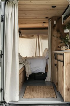 the interior of a camper van with its door open and curtains pulled back to reveal a bed