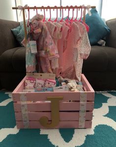 a pink trunk filled with baby clothes on top of a blue and white rug