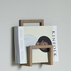 a magazine rack with two magazines on it and a wooden frame hanging from the wall