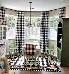 a dining room with black and white checkered curtains, green chairs and a table