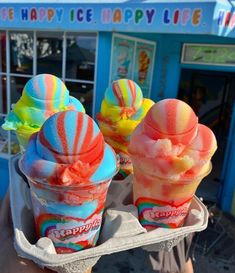 two scoops of ice cream in front of a candy shop with rainbow swirls