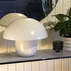 a white mushroom lamp sitting on top of a table next to a potted plant