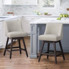 two stools in the middle of a kitchen with white cabinets and marble counter tops