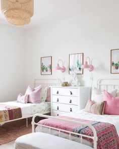 two beds in a room with pink and white decor