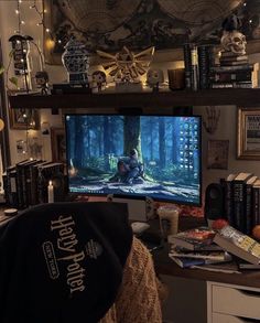 a flat screen tv sitting on top of a wooden desk next to a bookshelf