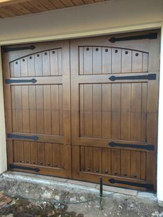 two wooden garage doors in front of a house