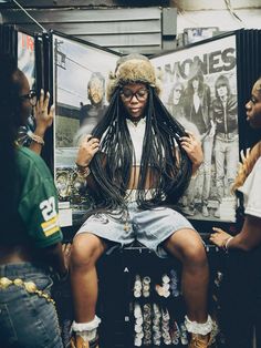 a woman sitting on top of a stool with dreadlocks in front of her