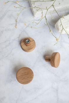 three wooden knobs sitting on top of a white marble counter next to a plant