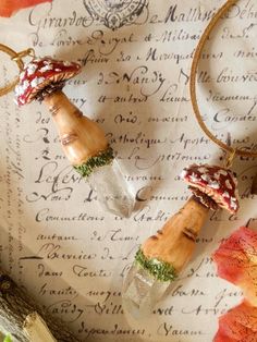 two necklaces made out of glass bottles on top of a piece of paper with leaves