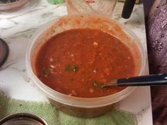 a plastic container filled with soup sitting on top of a table next to a pair of scissors